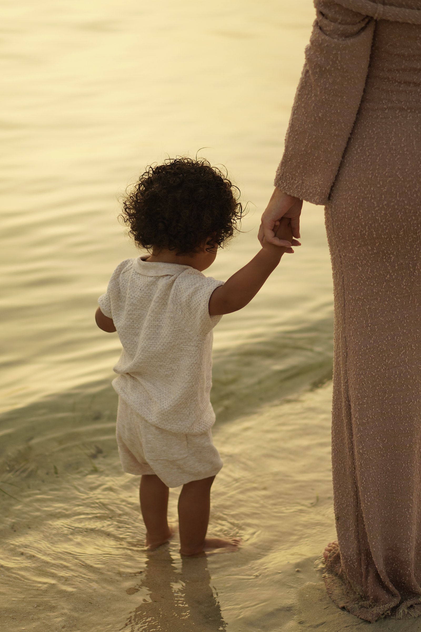A mother holding her toddler close, photographed in black and white against the water