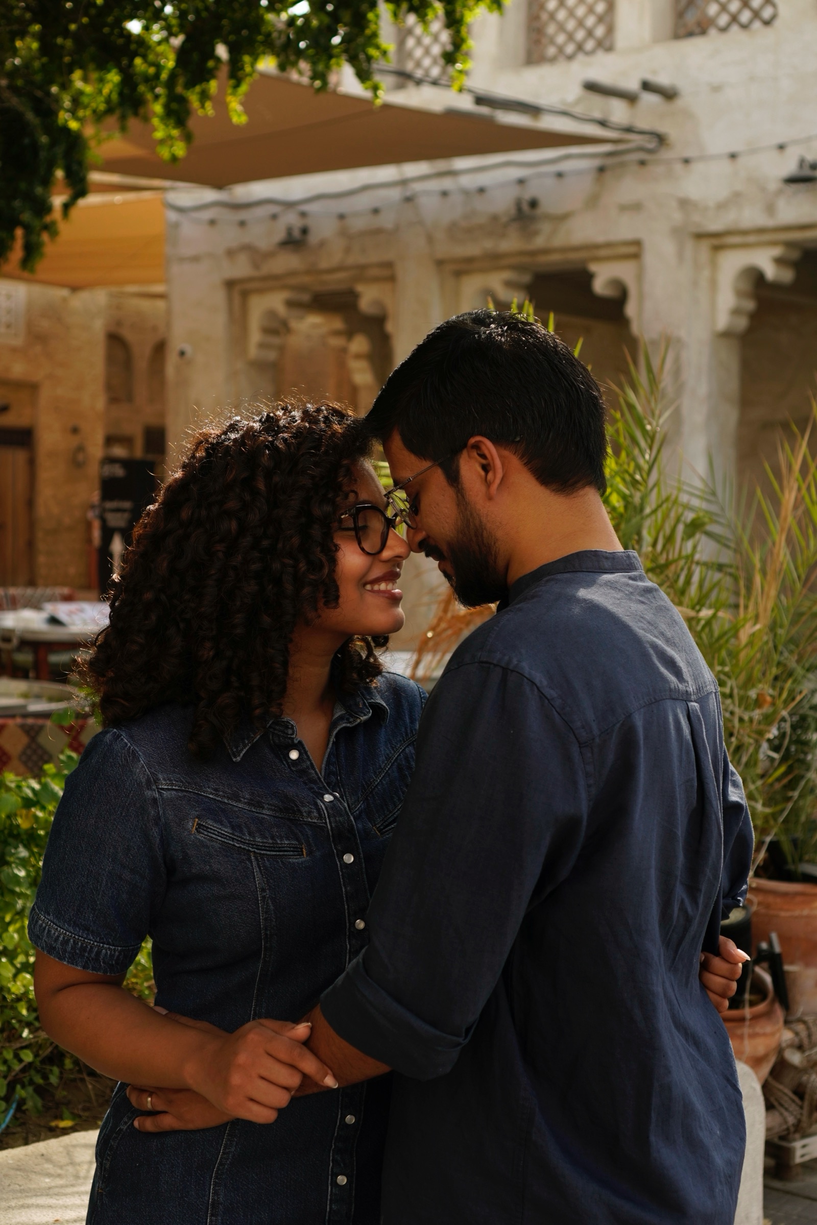 Couple in denim embracing among old town greenery