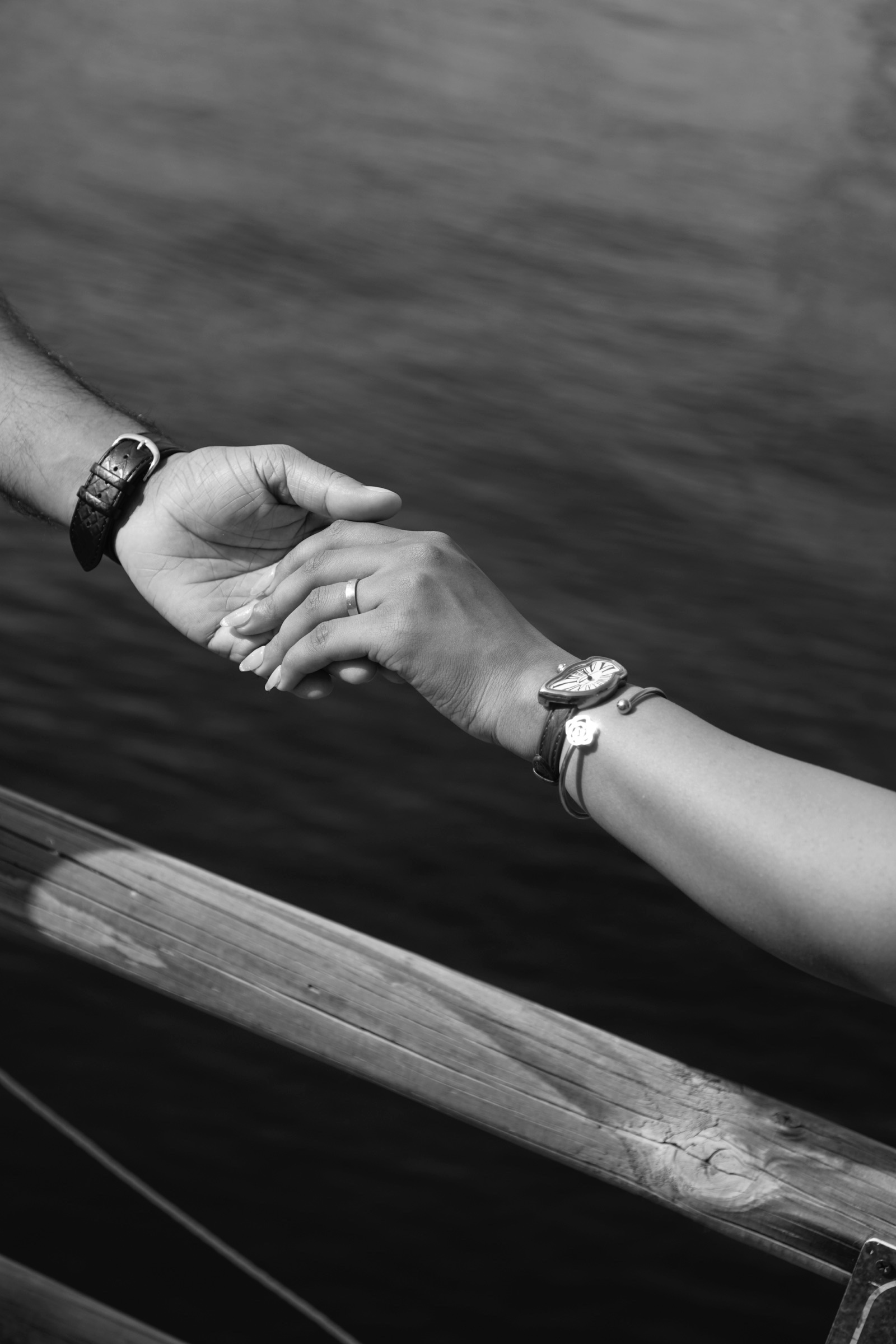 Held hands with ring and watch on a wooden boat, black and white