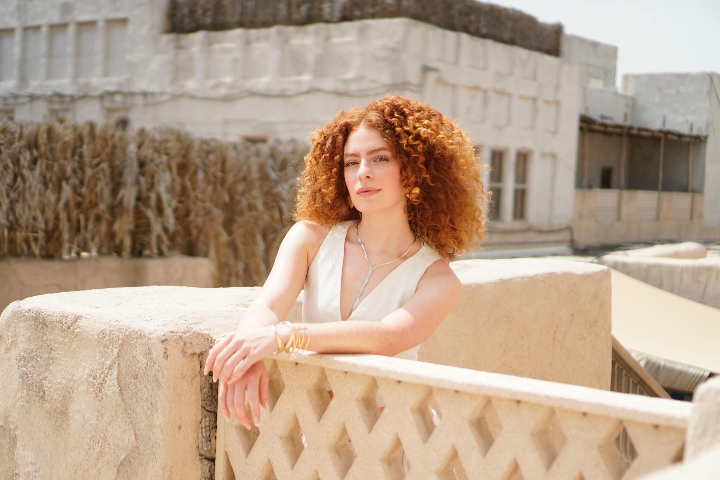 Woman in white leaning on a white balcony railing at Al Seef