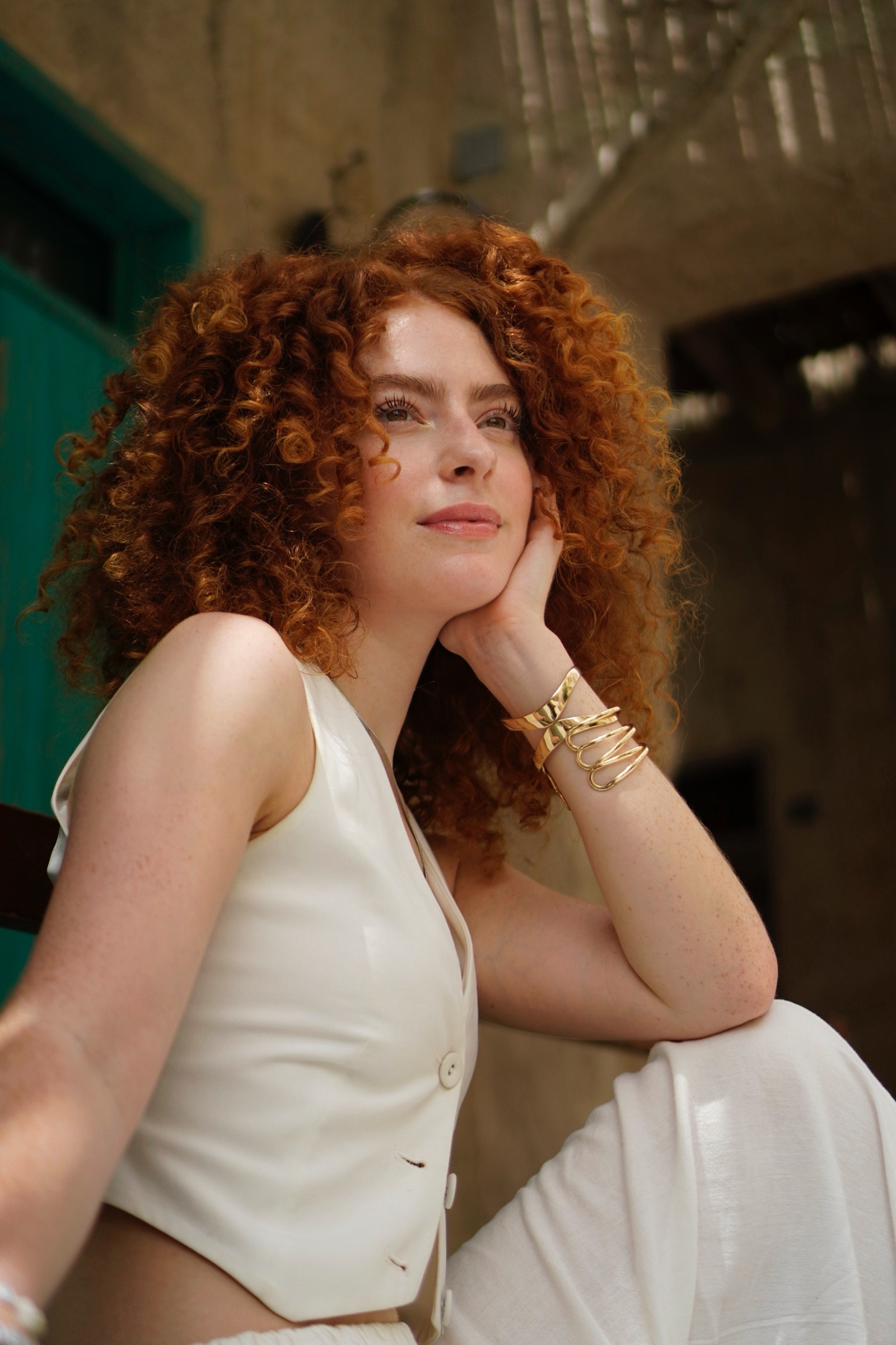Woman in white standing, hand to chin