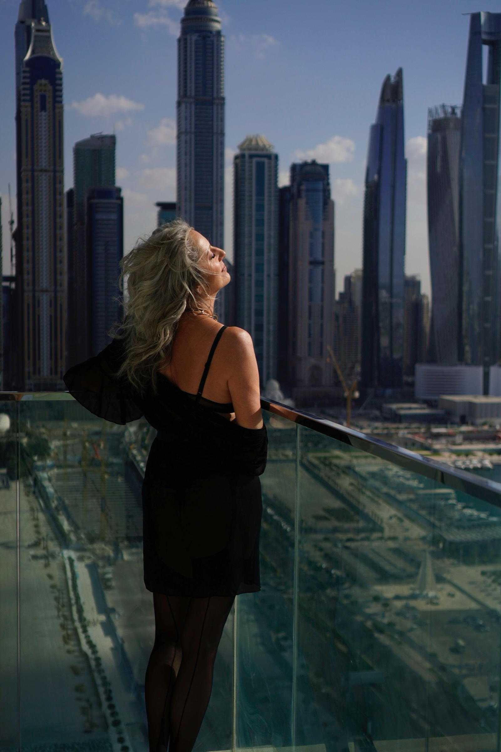 Boudoir on a balcony in a black slip, Dubai Marina behind