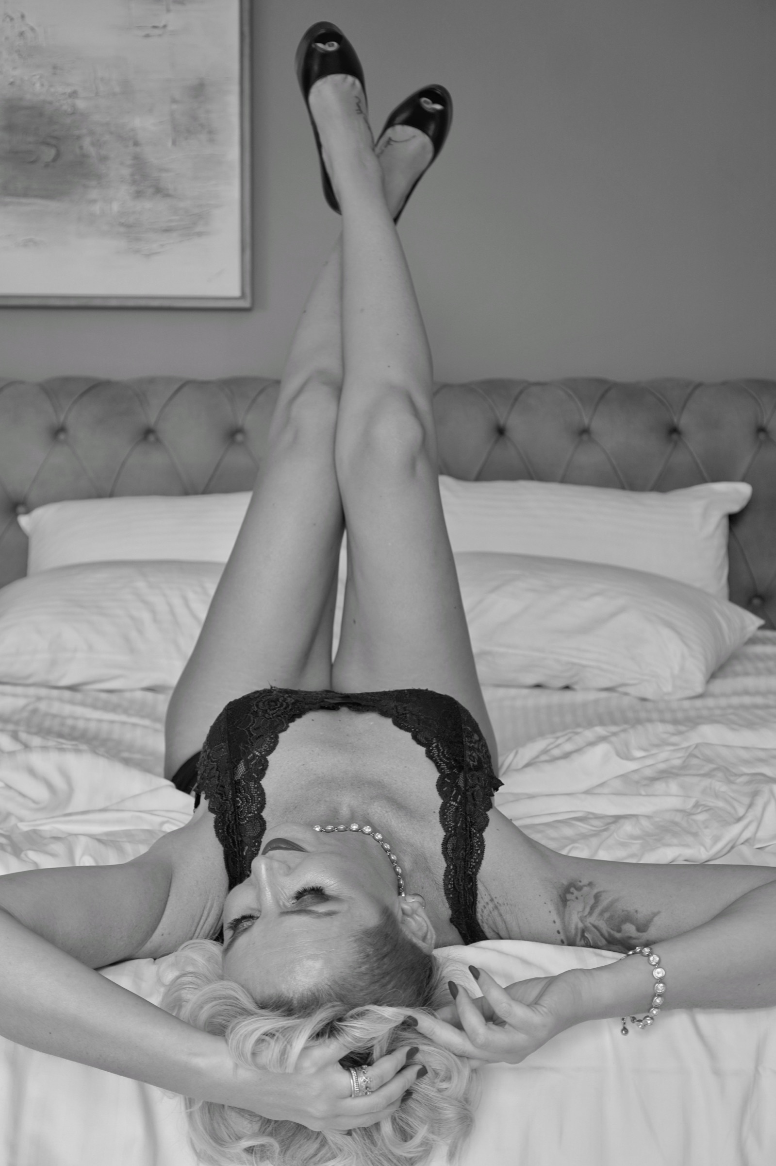 Boudoir portrait, legs raised on the bed in heels, black and white