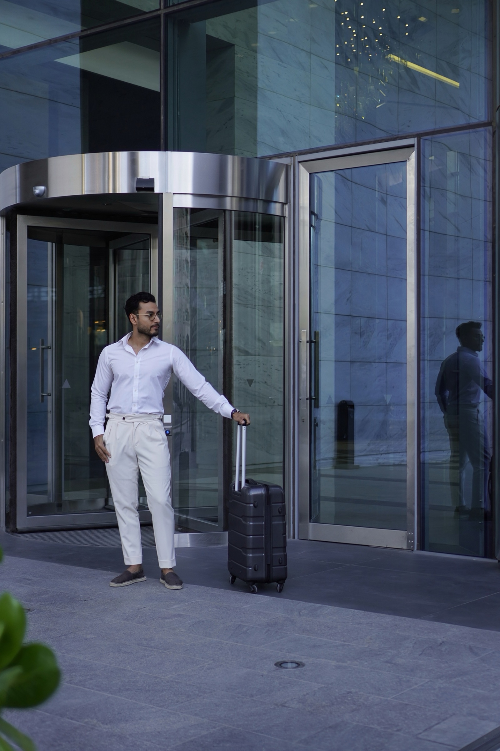 Businessman with luggage by a glass revolving door
