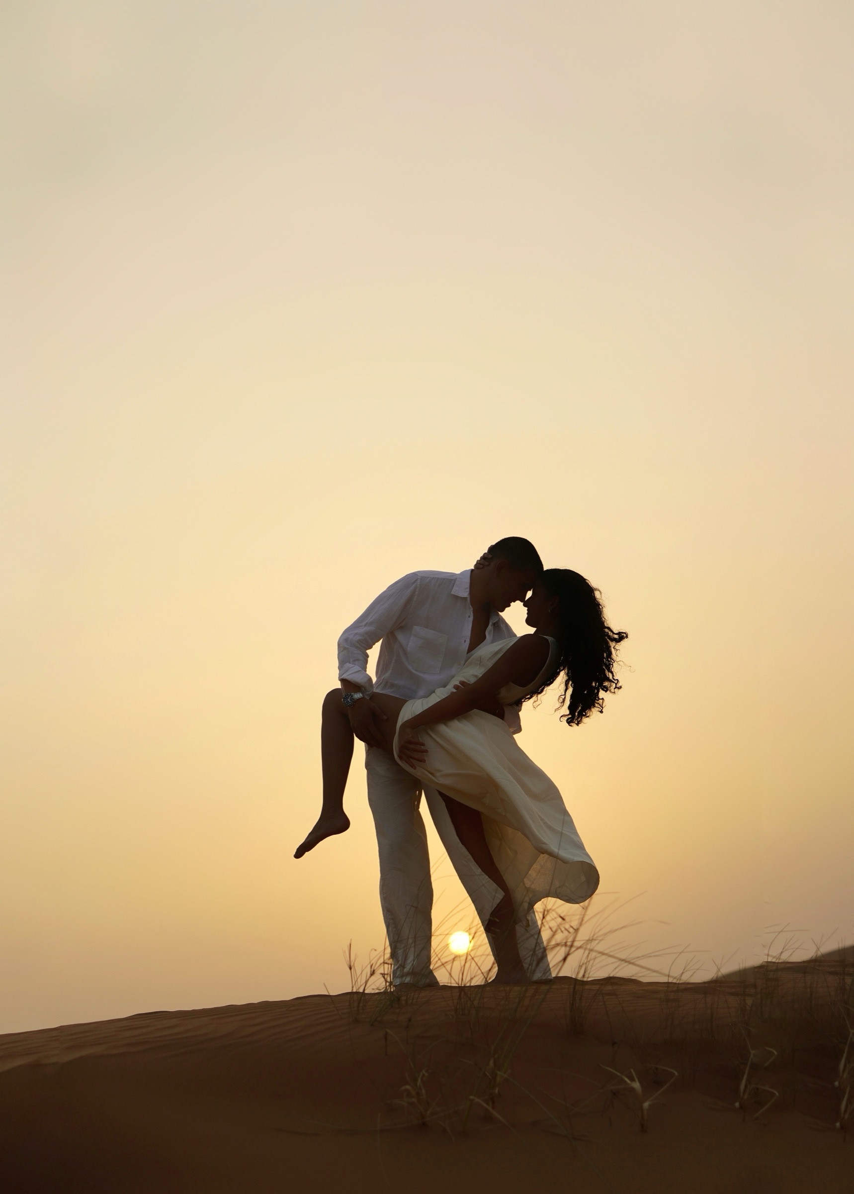 Couple embracing on a dune in golden desert light