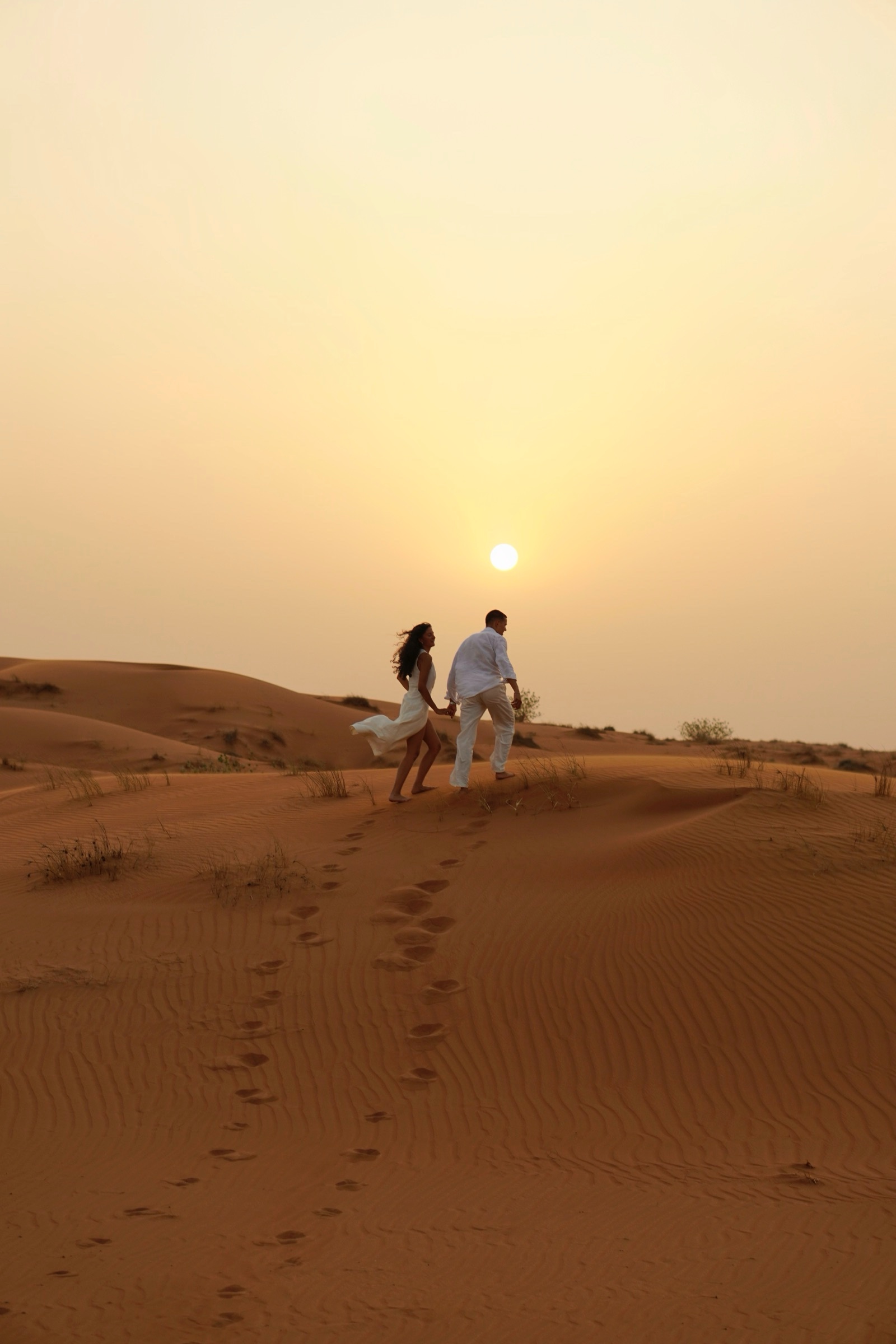 Couple walking toward the sun across the dunes