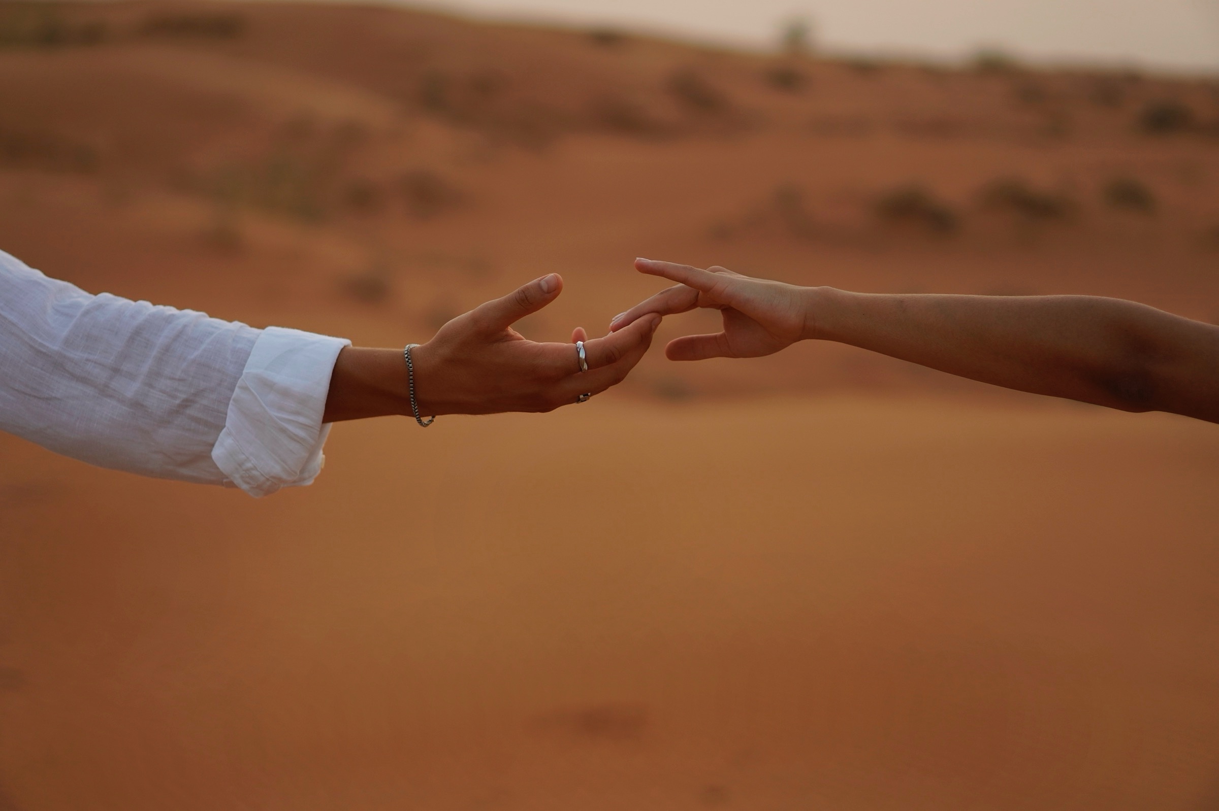 Hands reaching toward each other over the sand