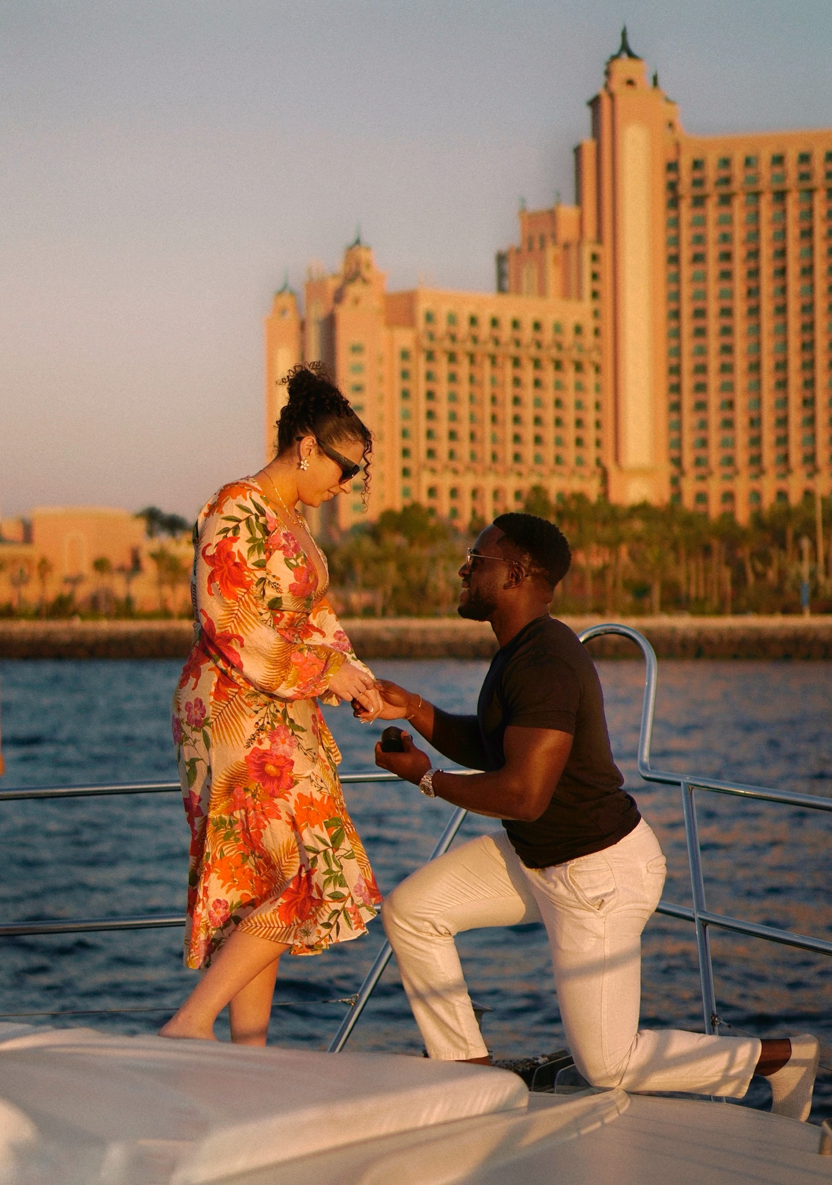 Man kneeling to propose on a yacht, Atlantis in the background