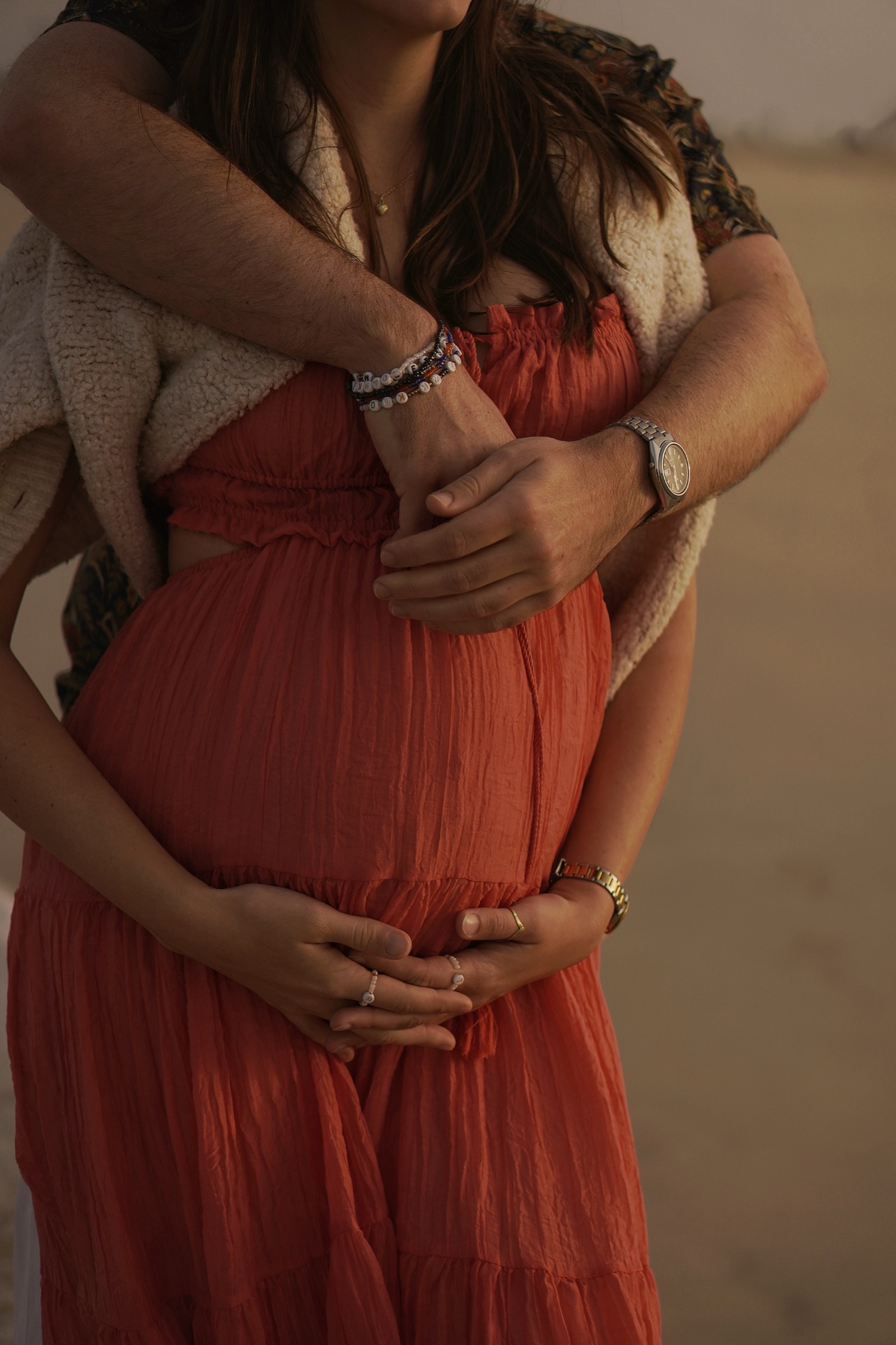 Expecting mother in a red dress, hands on the bump