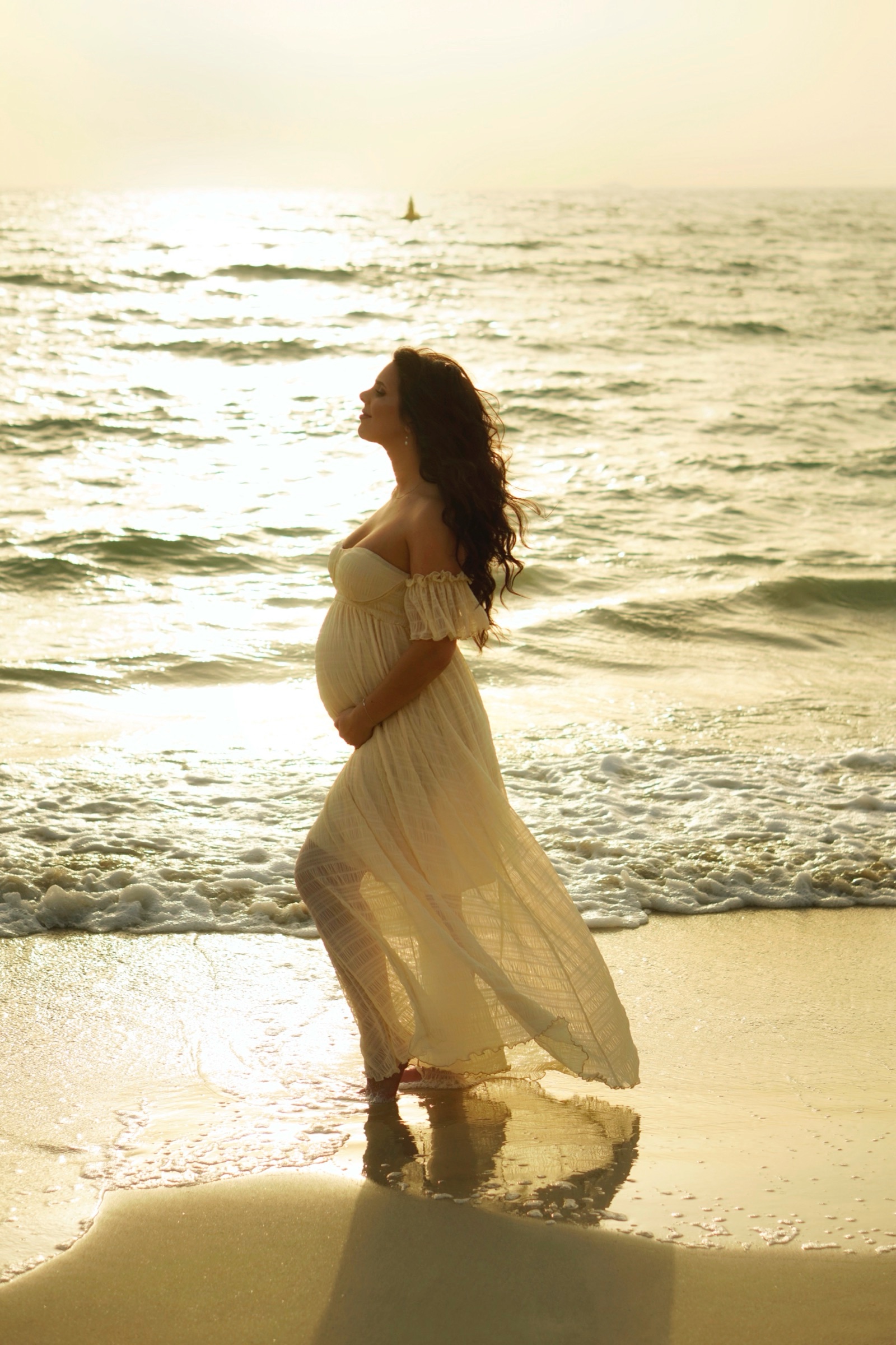 Expecting mother walking the shore in a yellow dress