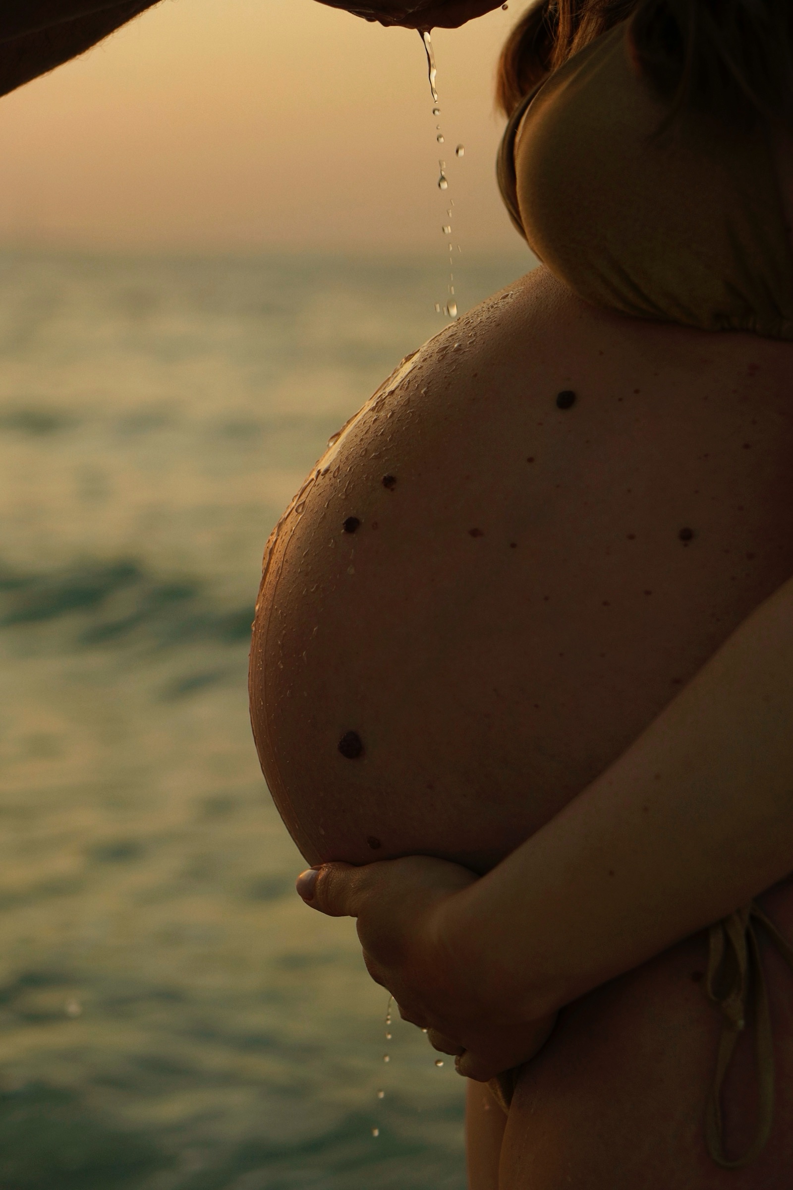 Baby bump by the sea in warm golden light