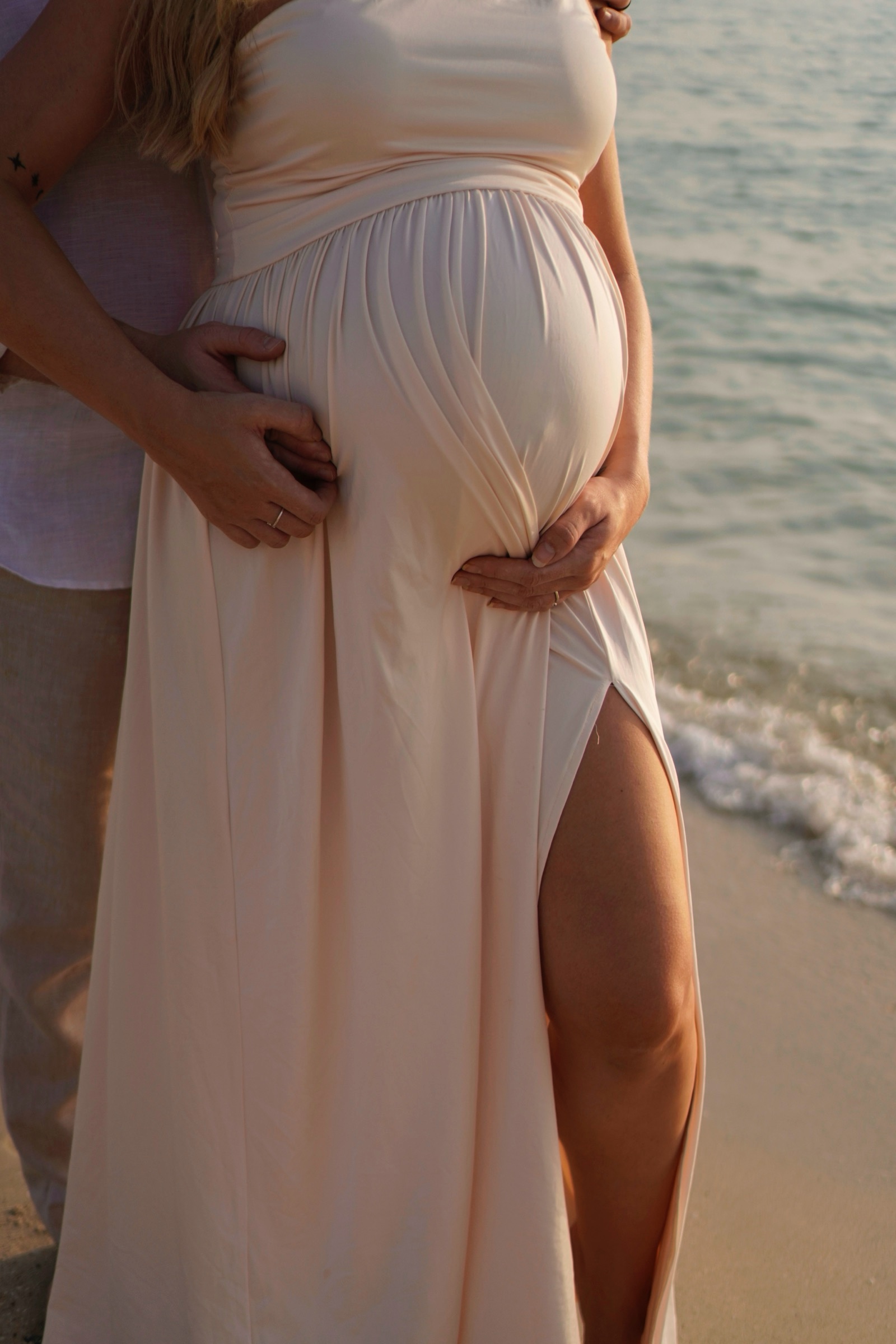 Hands cradling the bump in a white dress
