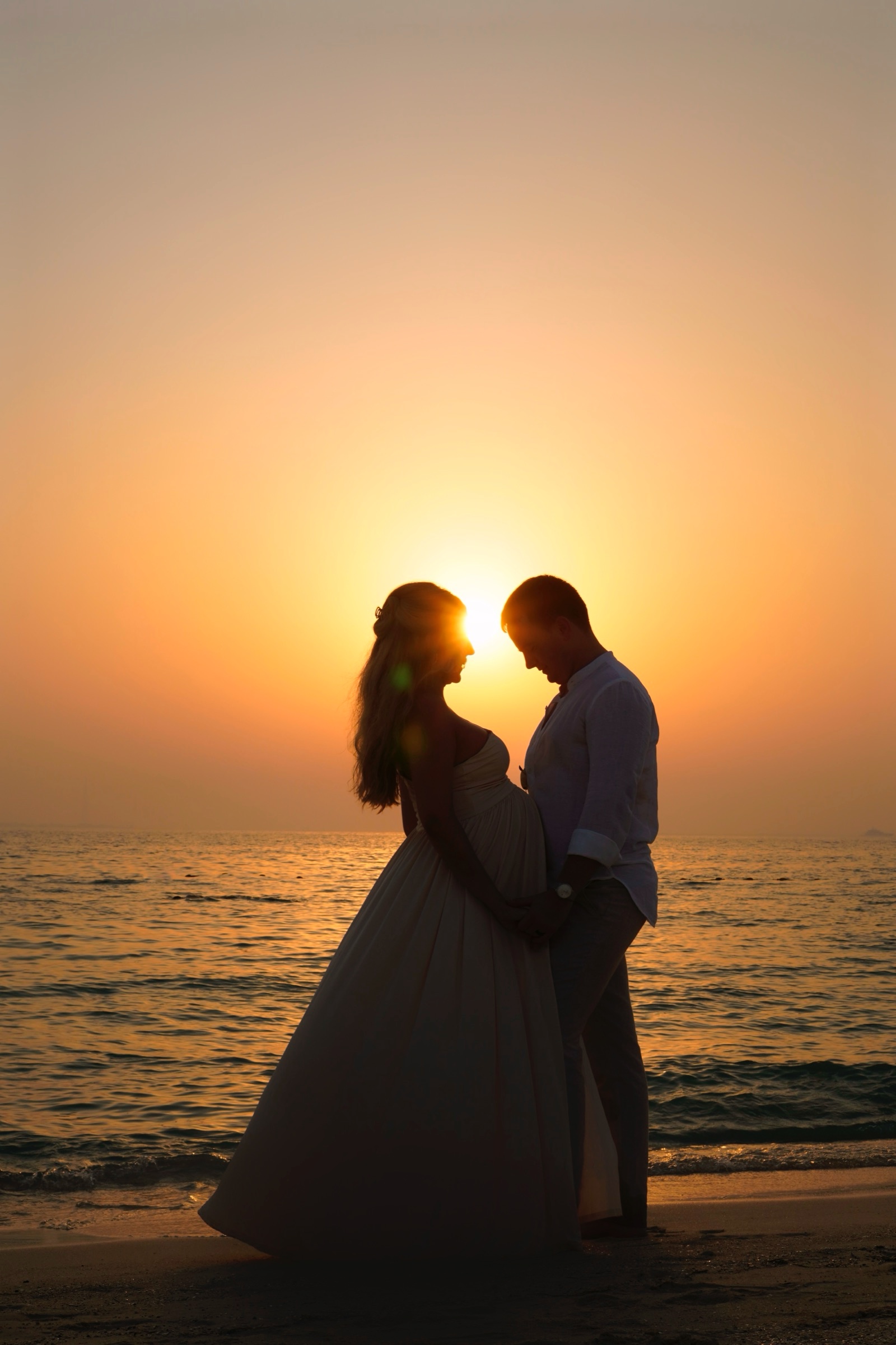 Couple silhouetted against the sun at the shore