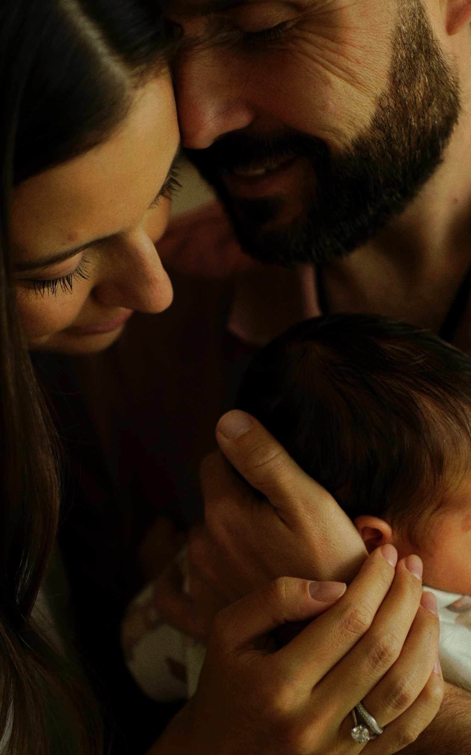 Parents smiling down at their alert newborn together