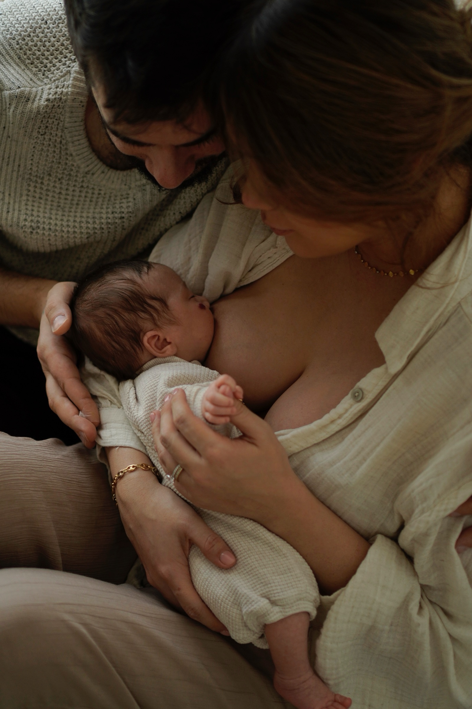 Close overhead of both parents cradling nursing newborn