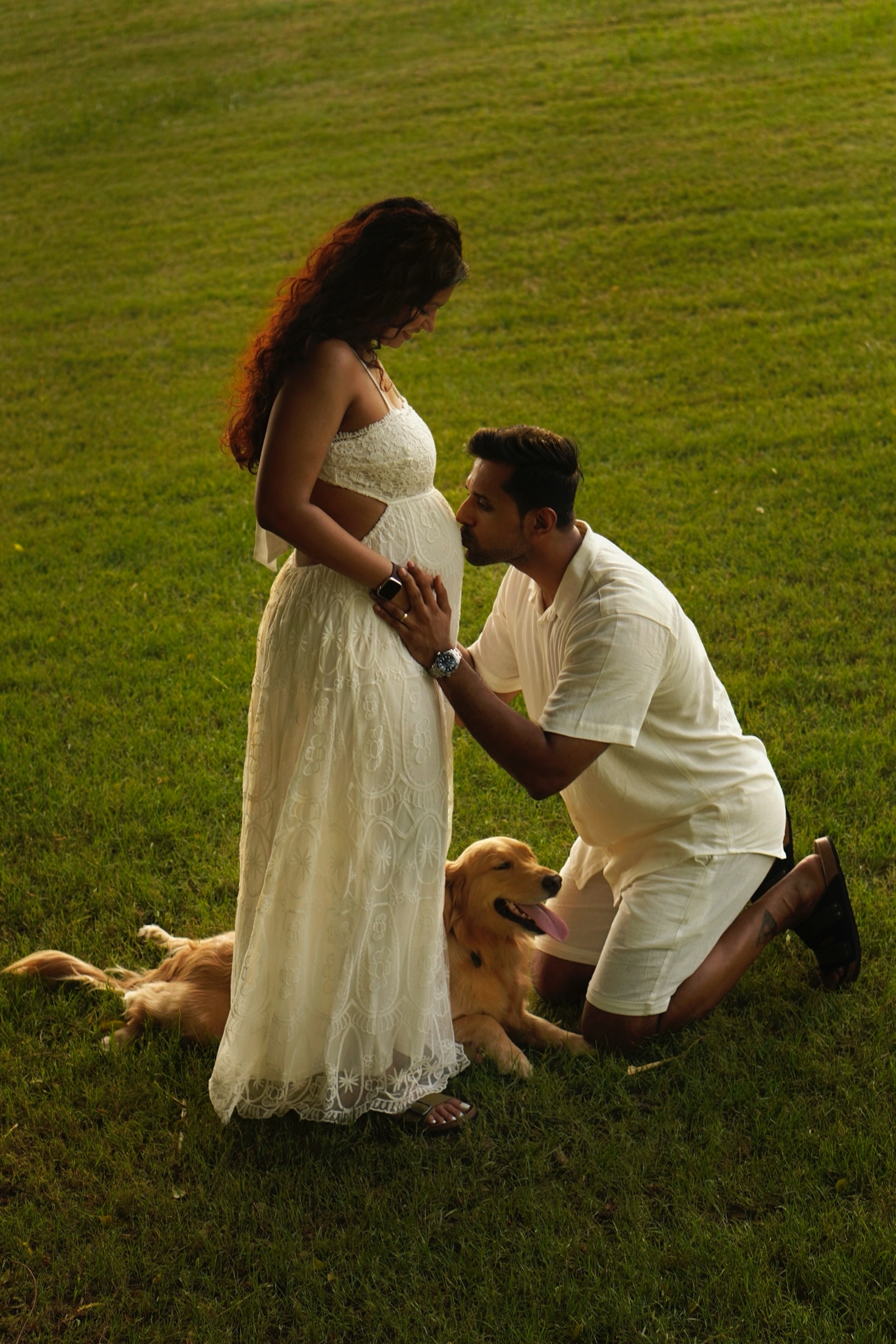 Couple kneeling in the grass with their dog