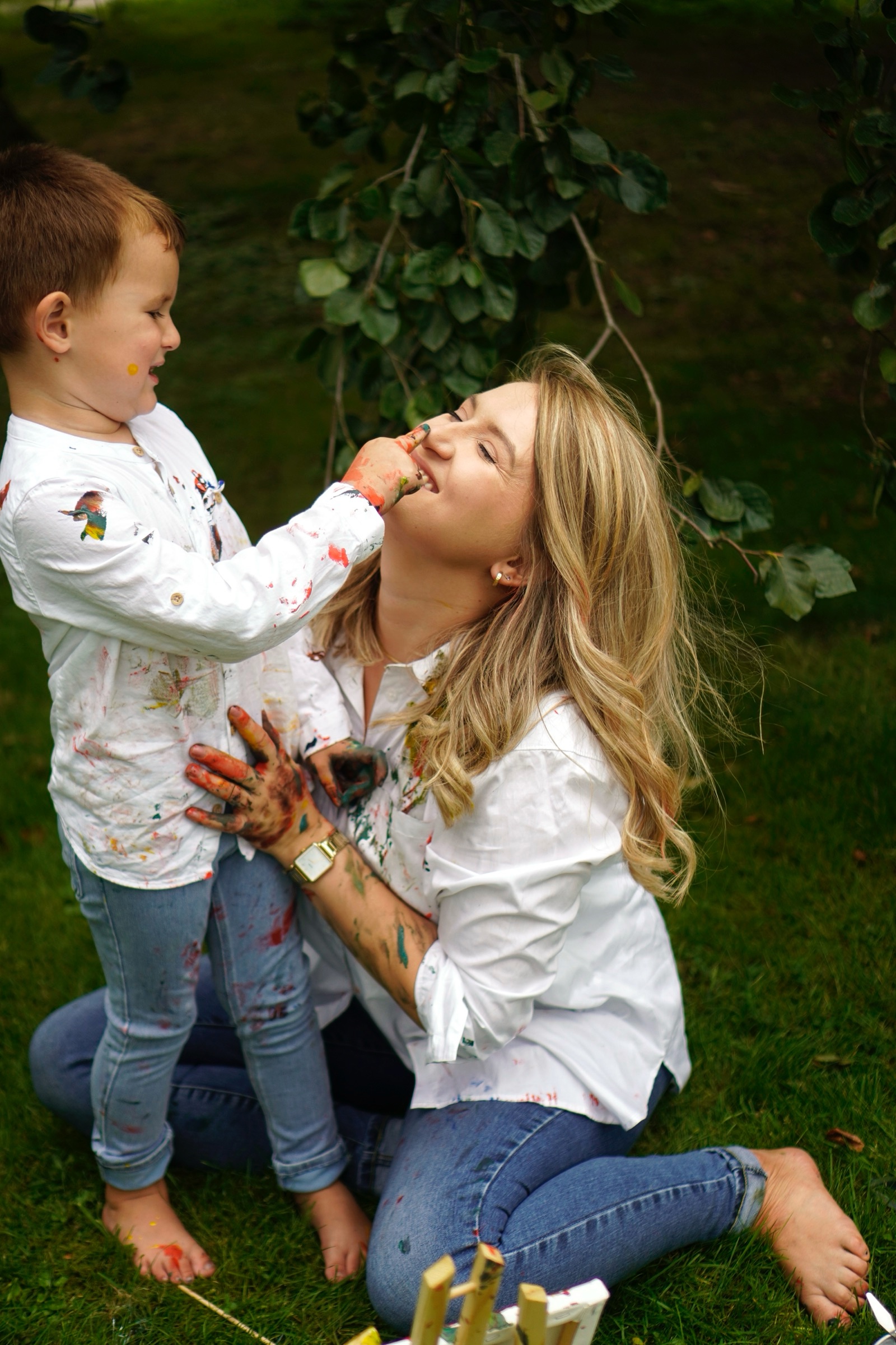Mother and son playing with paint in the grass