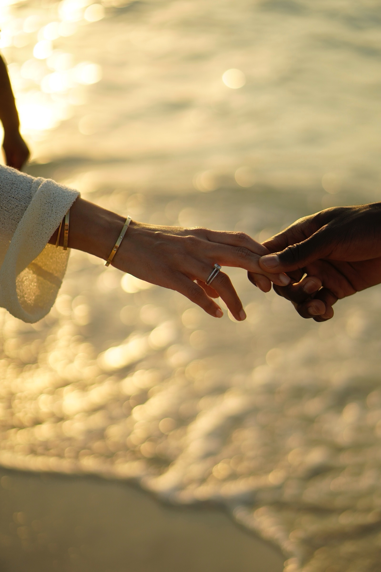 Couple touching fingertips with engagement ring bokeh
