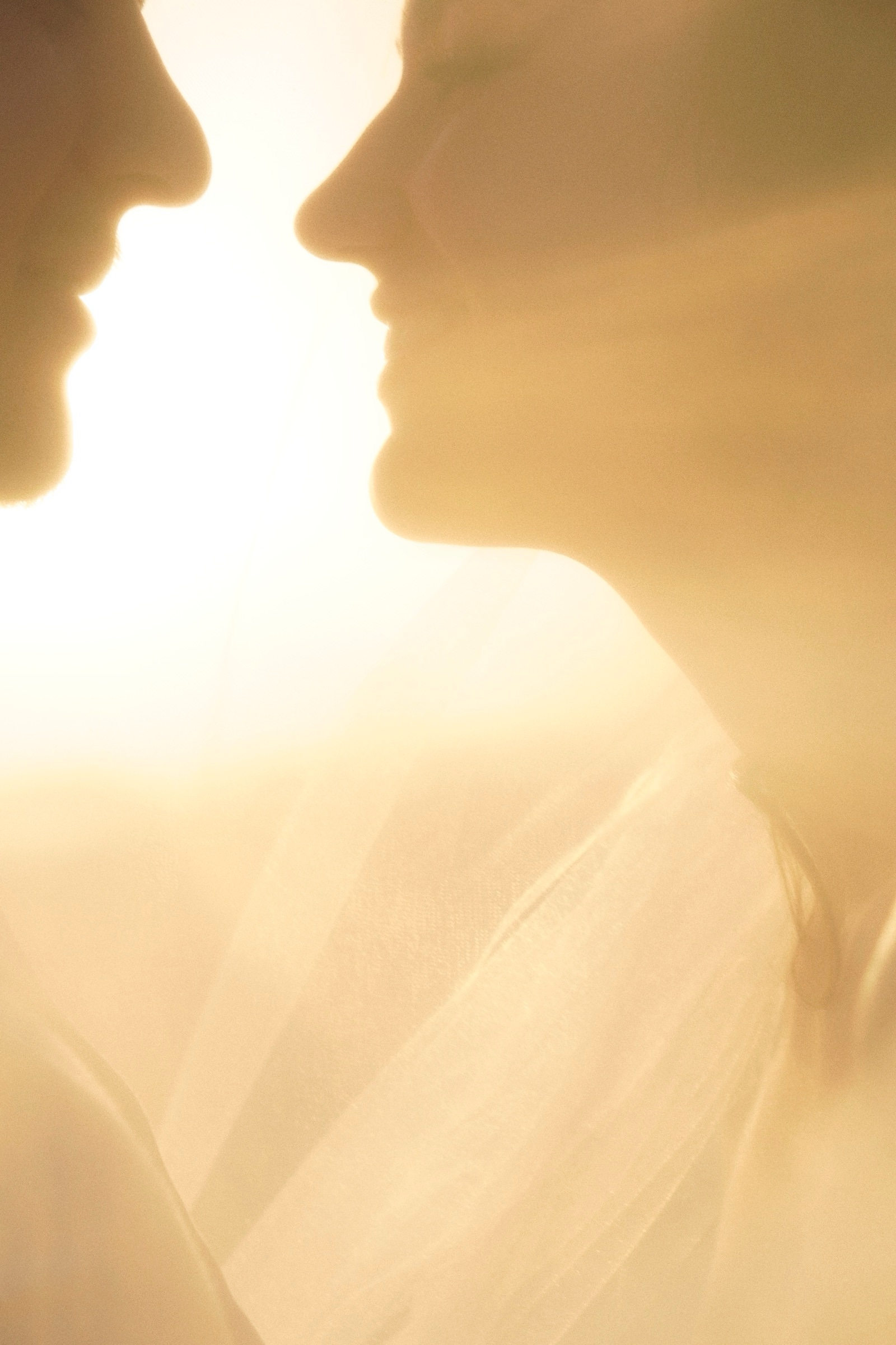 Bride and groom silhouetted against the sun