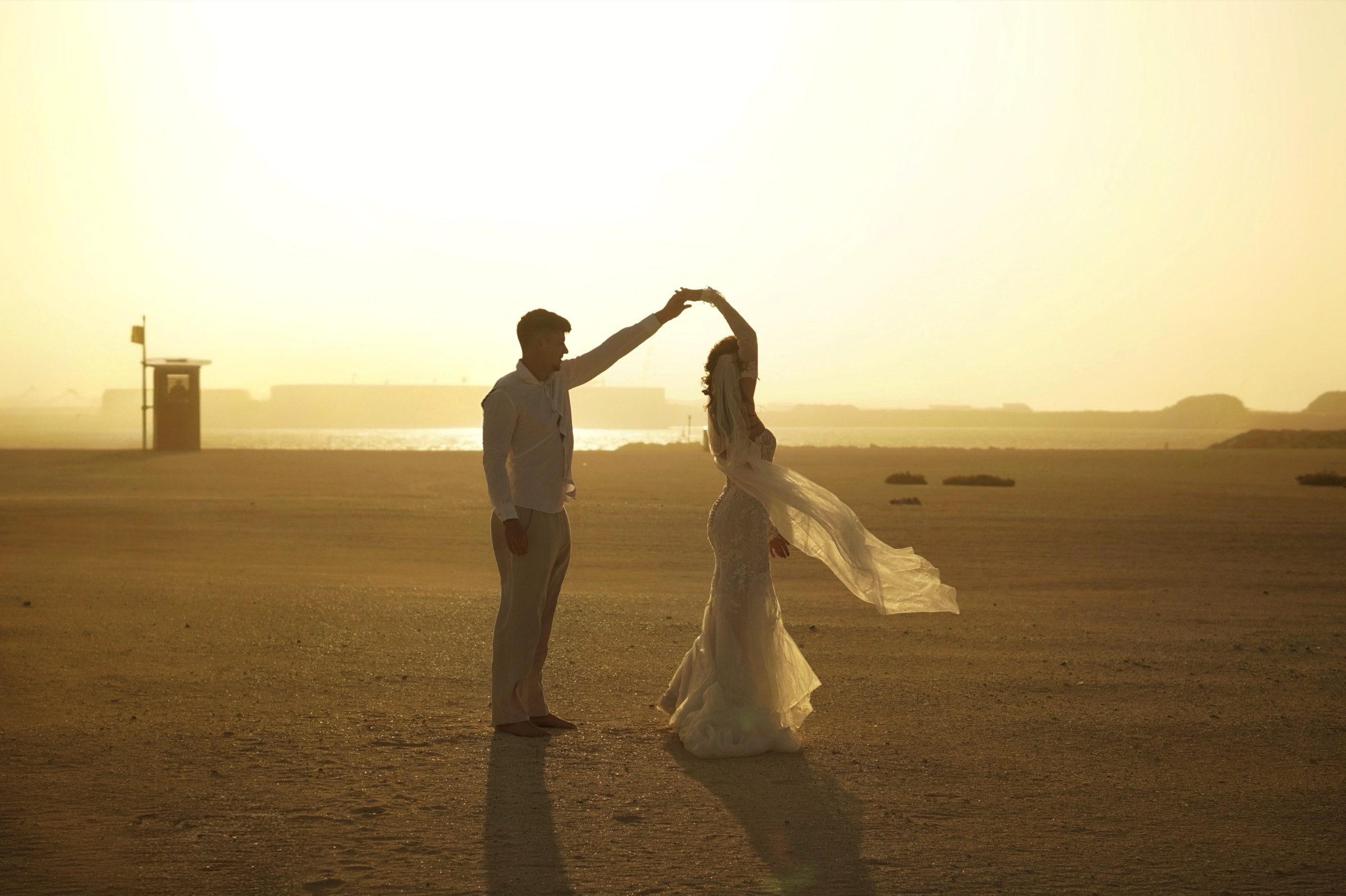 Couple twirling on the beach in golden light