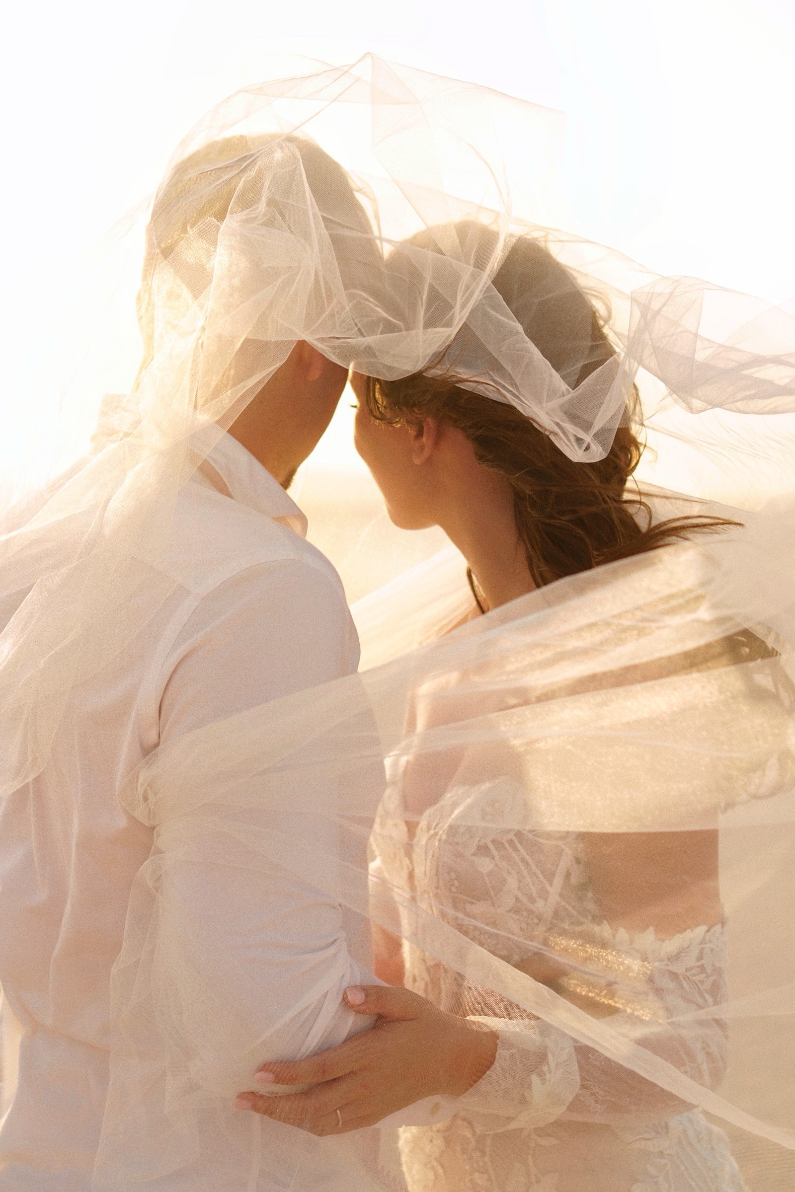 Couple beneath a veil, backlit by the sun