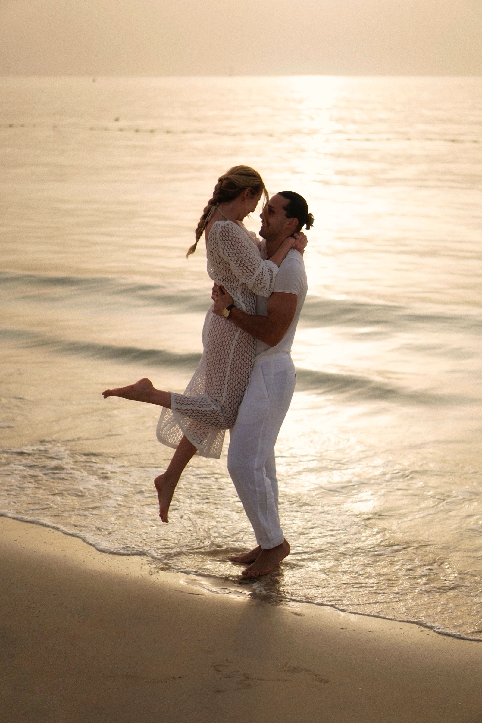 Man lifting woman kissing in waves