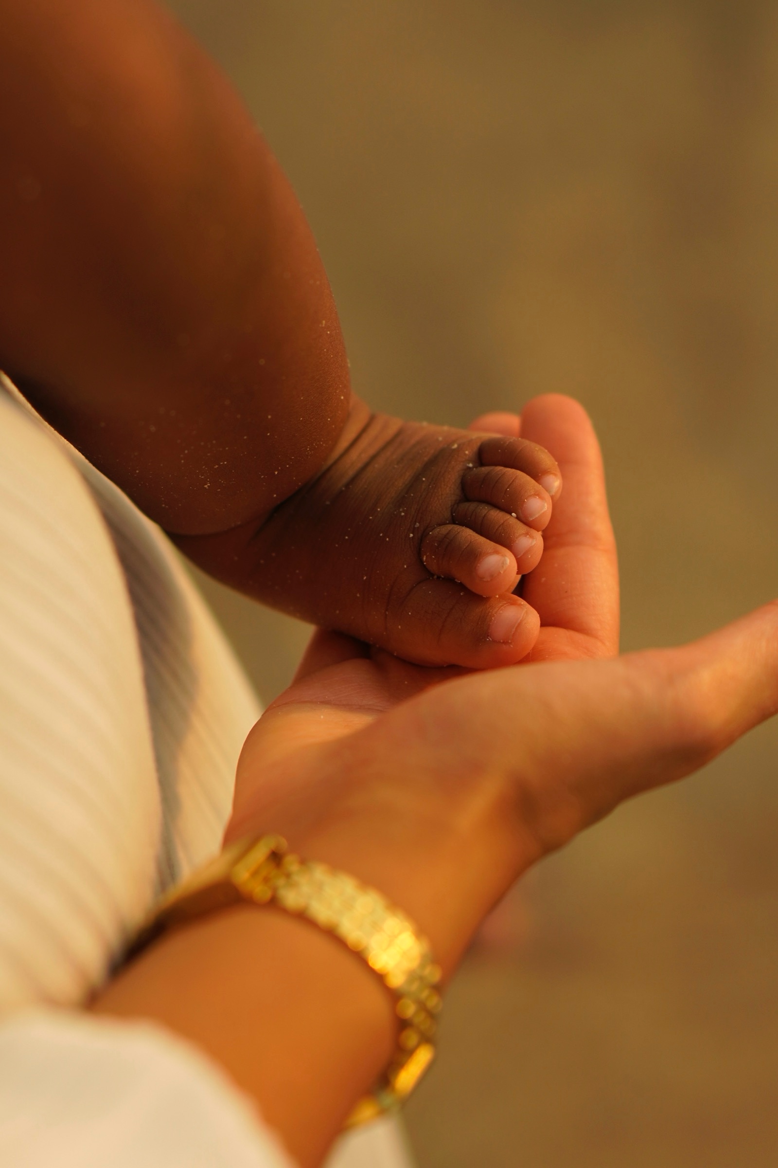 Baby's feet cradled in a hand at golden hour