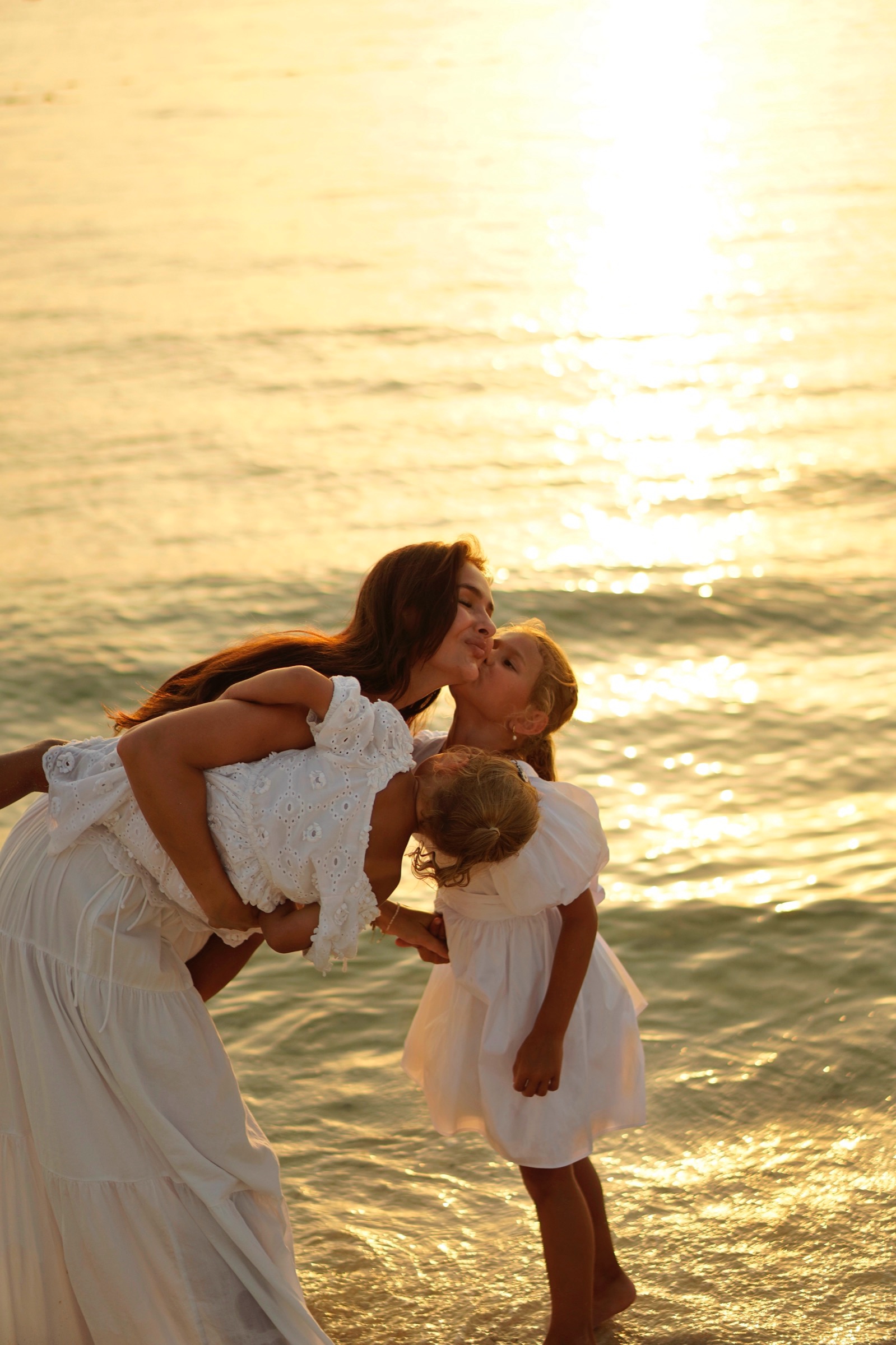 Father lifting and kissing his kids in the water