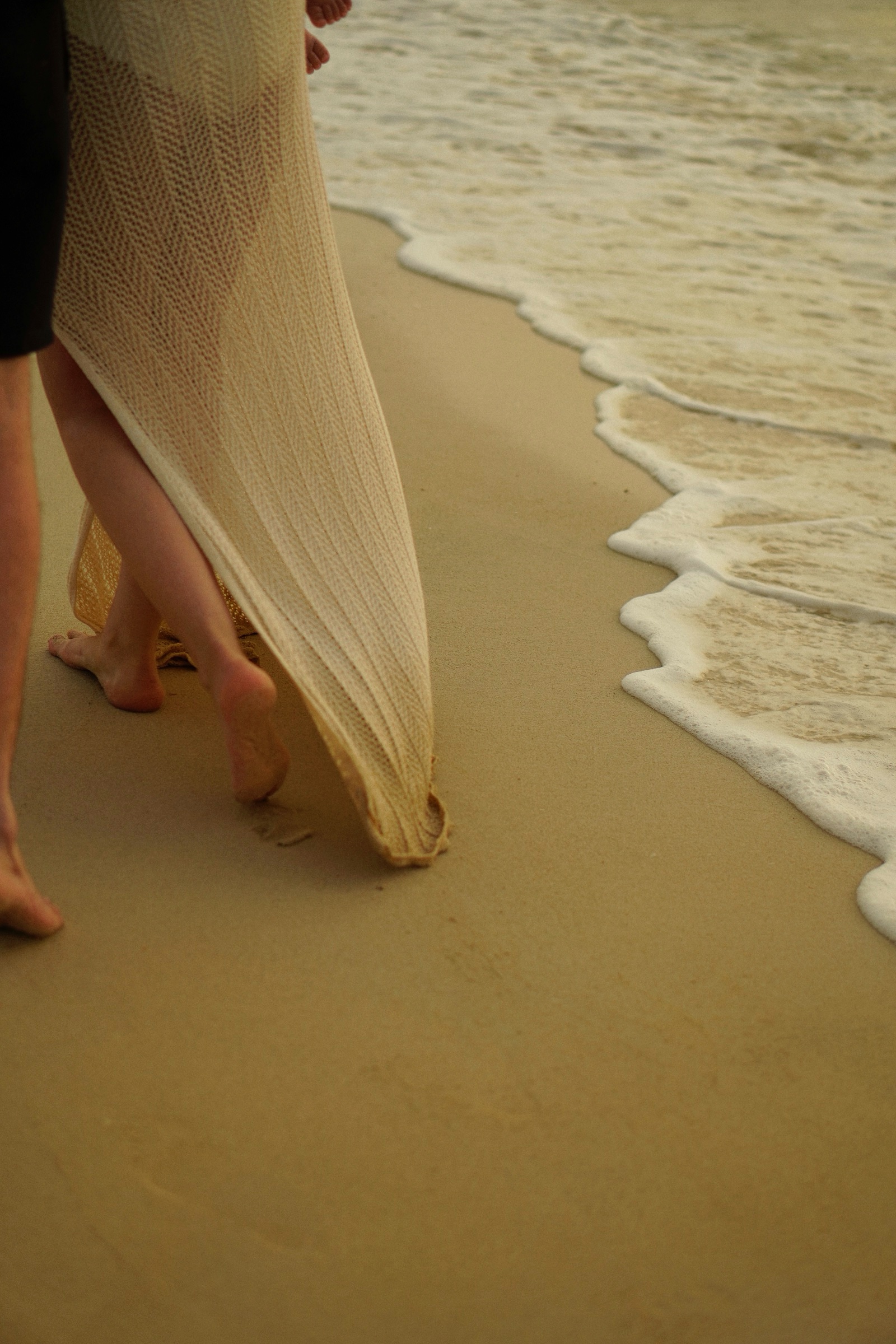 Flowing dress as mother walks the wet sand