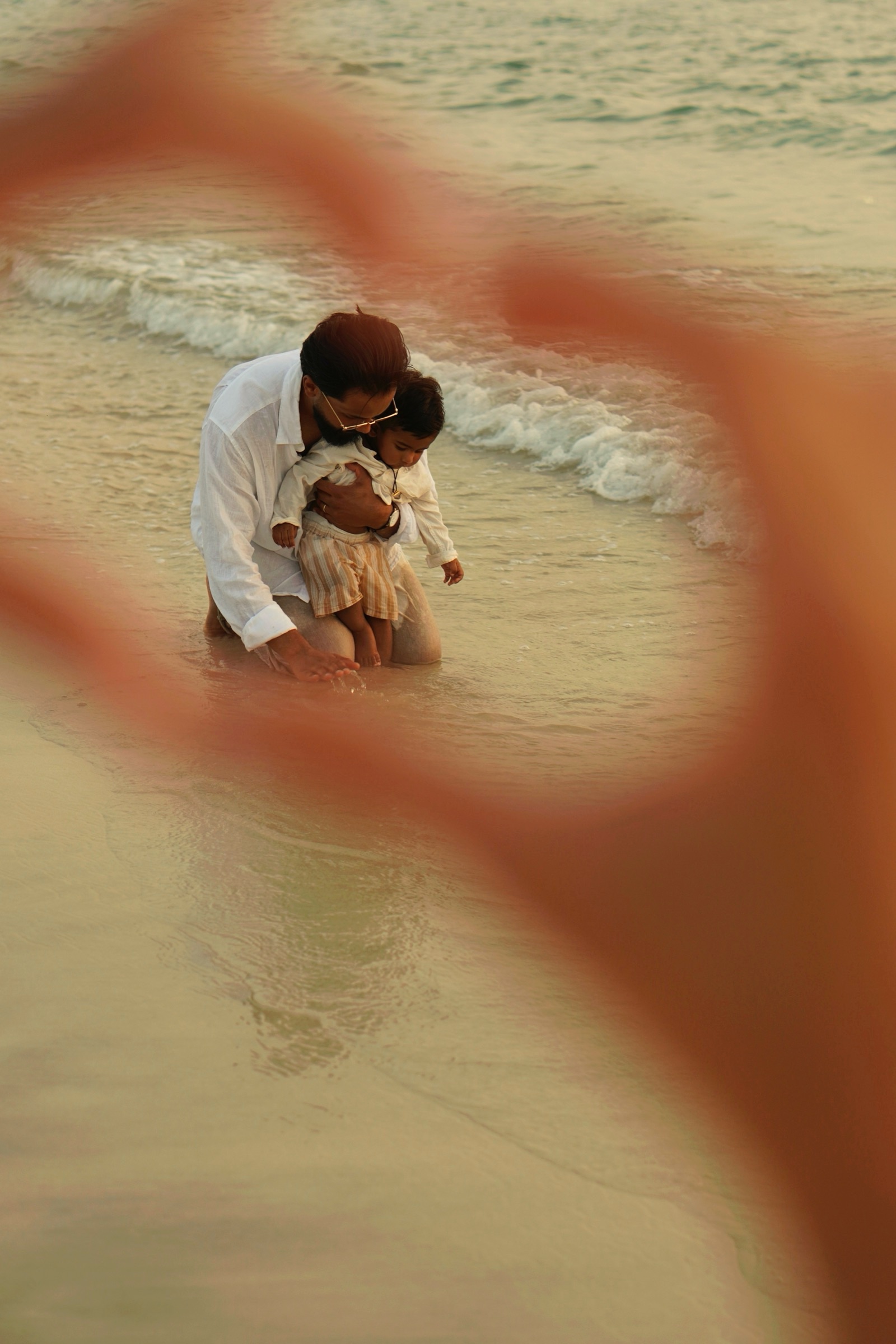 Family framed through heart-shaped hands