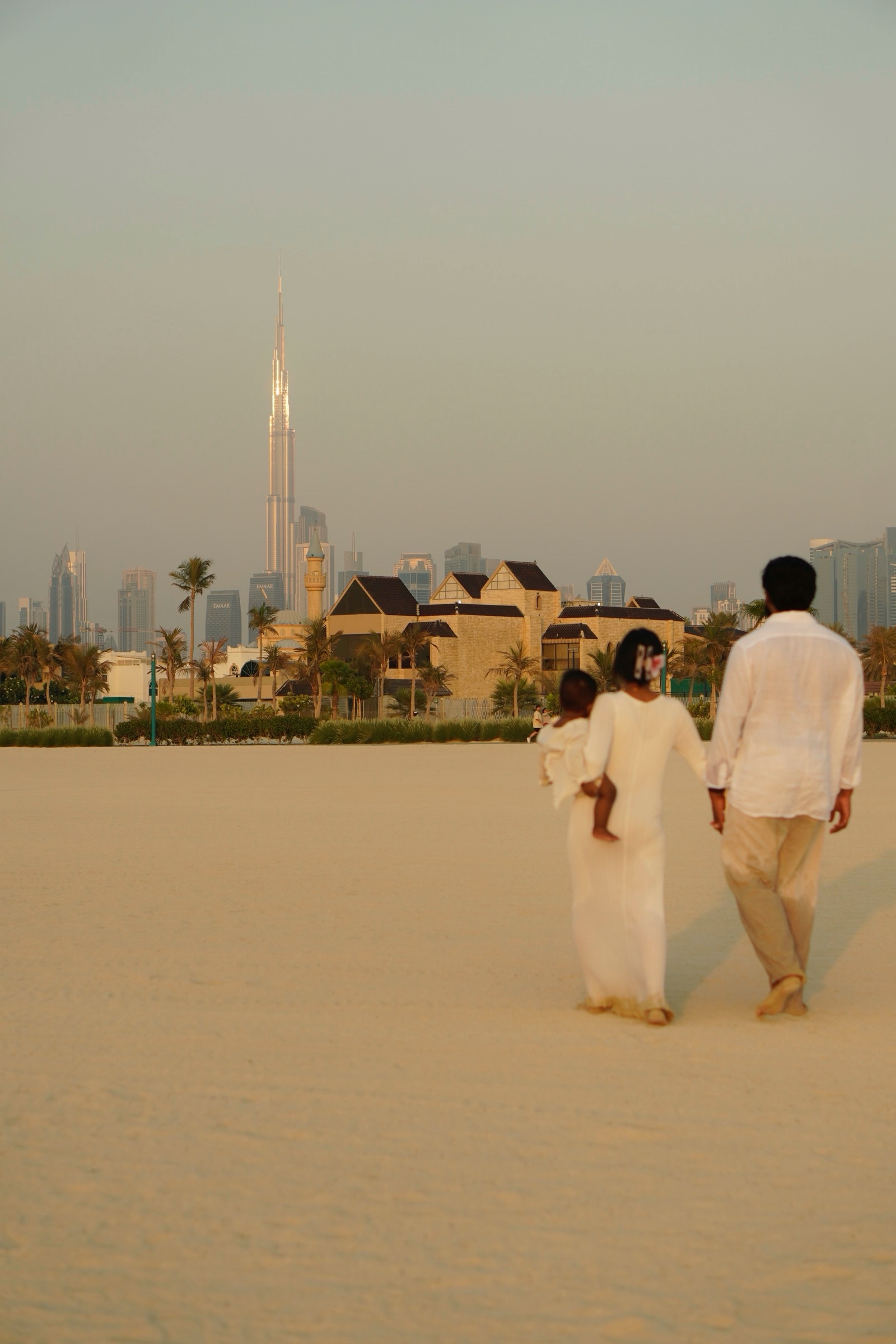Family walking the beach with the Dubai skyline behind