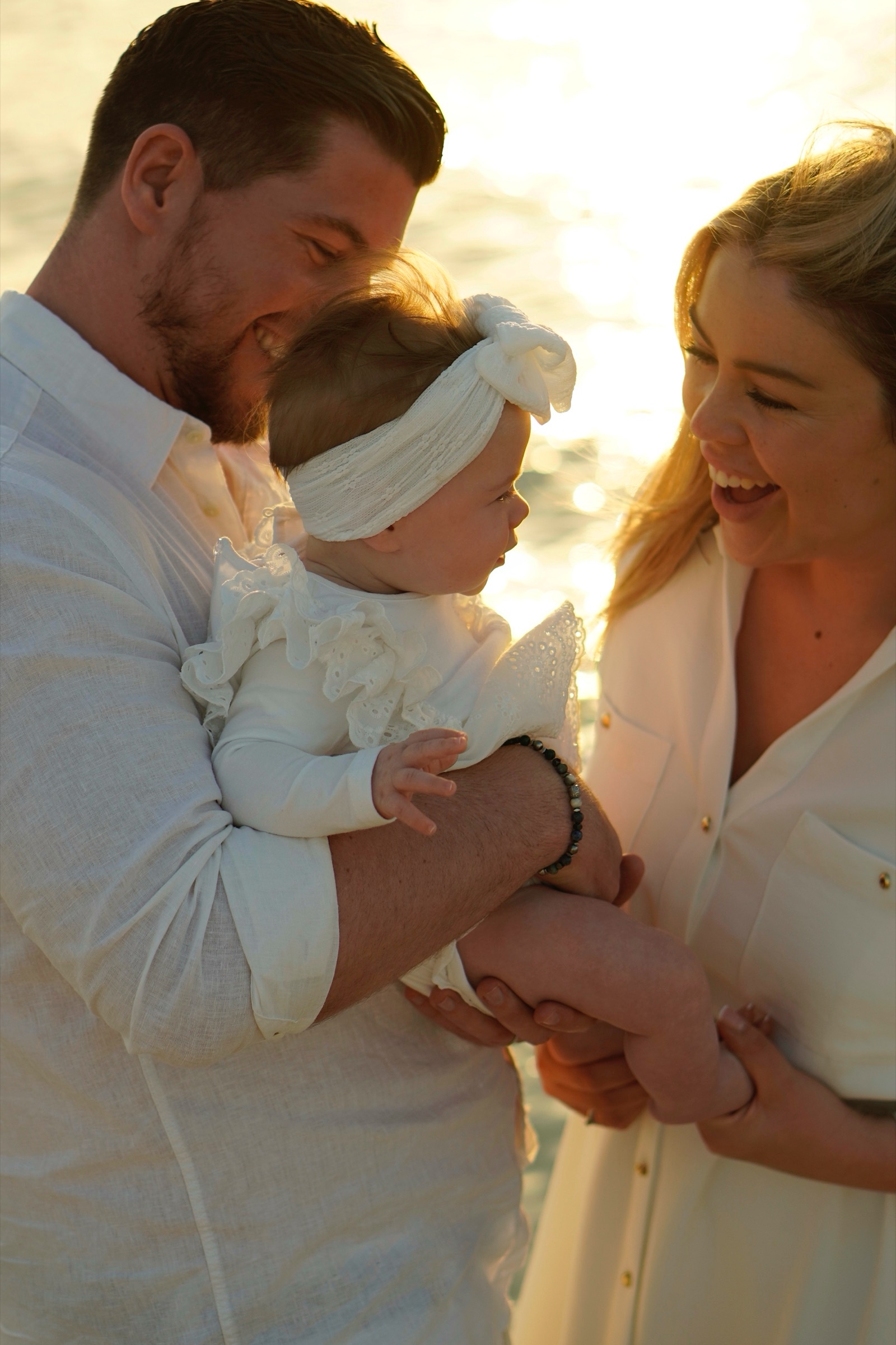 Parents smiling with their baby at sunset